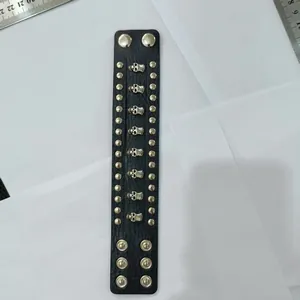 Detailed macro view of punk black leather bracelet with silver skull studs and rivets.
