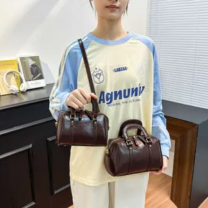 Showcasing two dark brown glossy leather Boston bags with adjustable shoulder straps