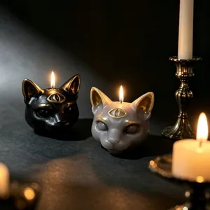 Atmospheric close-up of three-eyed cat candles with golden details in a dark gothic setting