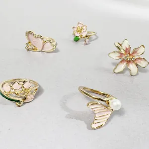 Detalle de un juego de 5 anillos dorados con motivos de flores y mariposas en esmalte
