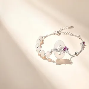 Detailed view of sterling silver bracelet with white beads and purple gemstone flower