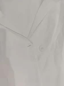 Close-up detail of a white commuter blazer collar and a single white button closure.