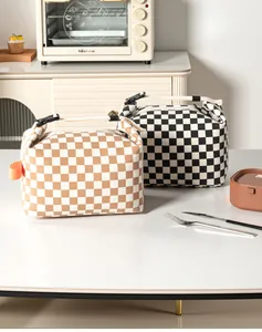 Two checkerboard insulated lunch bags displayed in a kitchen setting on a white table