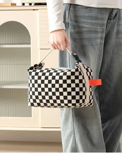 Close-up of checkerboard corduroy insulated lunch bag with orange pull tab detail