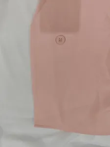 Close-up of pink fabric texture and matching button of a stylish commuter suit set
