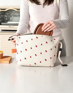 Close-up detail of a corduroy insulated lunch bag with strawberry pattern being used