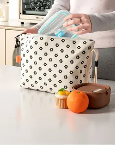 Detailed view of a floral corduroy insulated lunch bag being filled with containers.