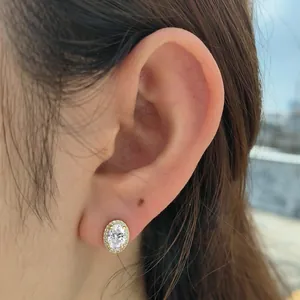 Elegant oval halo cubic zirconia stud earrings in gold-plated silver on ear model
