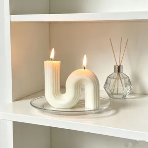 Elegant white S-shaped geometric scented candle with two flames on a clear glass plate
