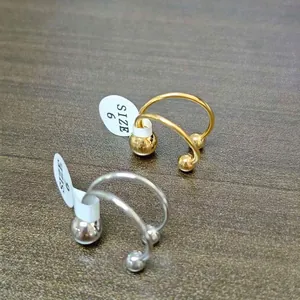 Detailed view of minimalist gold and silver stainless steel ball rings with size tags