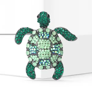 Close-up of elegant turtle brooch encrusted with vibrant green and blue crystals.