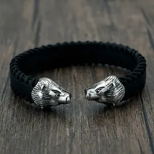 Detailed macro view of silver bear head carvings on a black braided leather cuff