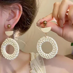 Elegant bohemian style woven rattan hoop earrings with gold studs and resin detail