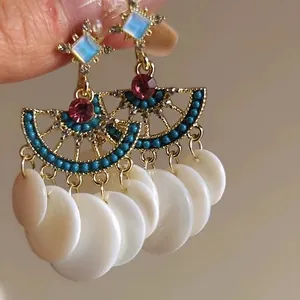 Gros plan détaillé de boucles d'oreilles éventail vintage avec pompons en résine blanche