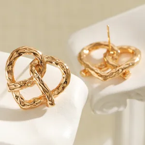 Primo piano di orecchini a lobo a forma di pretzel placcati in oro con texture martellata