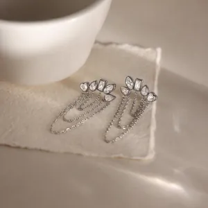 Macro detail of silver stainless steel earrings with white zircon and chain fringe