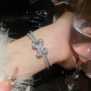 Detailed view of a sparkling zircon butterfly double-layer open bangle on wrist.