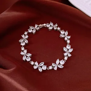 Detailed close-up of sparkling zircon flower bracelet on elegant red silk background.