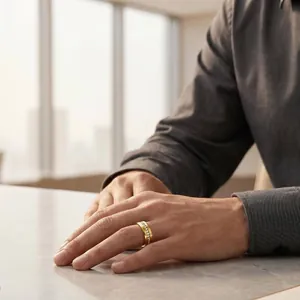 Close-up of a men's gold stainless steel ring with a single row of inlaid diamonds on a hand.