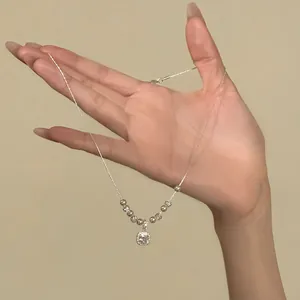 Elegant square zircon and pearl necklace displayed on hand, minimalist design.
