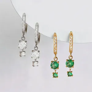 Dettaglio orecchini in acciaio oro e argento con pietre verdi e trasparenti brillanti