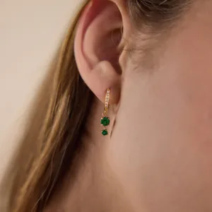 Primo piano di orecchini in acciaio dorato con pendenti in zircone verde scintillante