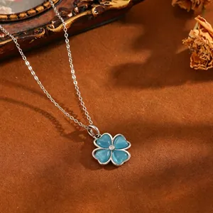 Detailaufnahme einer silbernen Kleeblatt-Halskette mit blauen Katzenaugen-Steinen.