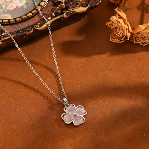 Detailansicht eines rosa Kleeblatt-Anhängers an einer silbernen Kette mit Vintage-Deko.