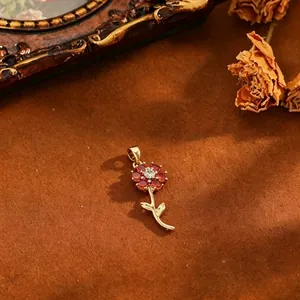 Eleganter roter Zirkonia-Blumenanhänger mit Goldbeschichtung auf warmem braunem Grund