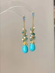 Detail van vintage druppeloorbellen met turquoise stenen en parelkwastjes