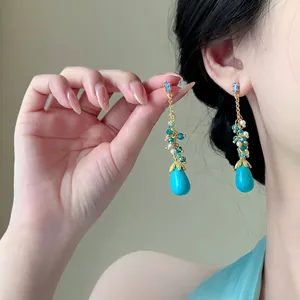 Detailopname van vintage etnische druppelkwast oorbellen met turquoise kralen.