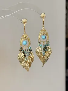 Detailopname van vintage goudkleurige bladkwastjes oorbellen met turquoise kralen.
