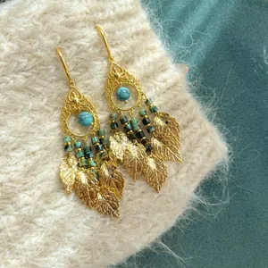 Gedetailleerd zicht op vintage etnische oorbellen met turquoise kralen en gouden blad.