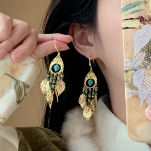 Close-up van vintage gouden kwastoorbellen in etnische stijl met turquoise op model