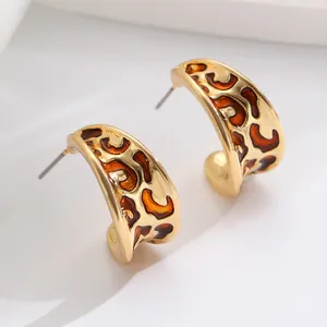 Detaillierte Makroaufnahme von goldenen C-Ohrringen im Vintage-Look mit Leopardenmuster