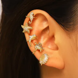 Gold ocean-themed ear cuffs set with seahorse and starfish designs on a human ear