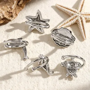Macro view of silver ocean-themed ear cuffs featuring seahorse and starfish on sand