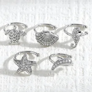Macro view of ocean-themed silver ear cuffs with turtle shell starfish seahorse dolphin