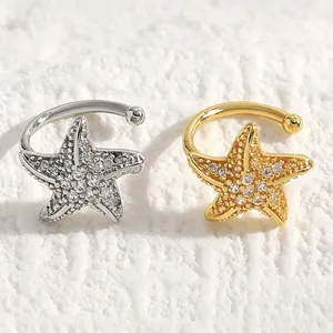Close-up of gold and silver starfish ear clips with sparkling zircon stones.