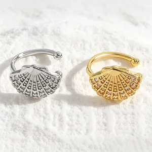 Detailed view of silver and gold shell ear clips with sparkling zircon inlay on sand