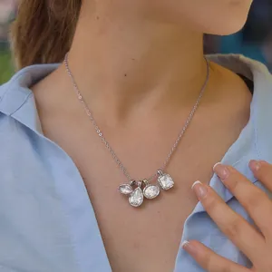 Elegant silver zircon necklace with four geometric charms on female model.