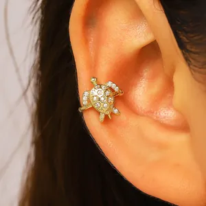 Detailed view of a sparkling gold turtle-shaped ear cuff with zirconias on a human ear