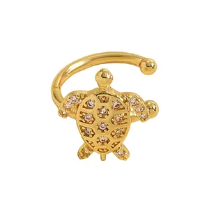 Detailed view of golden sea turtle ear cuff inlaid with shimmering pink cubic zirconia