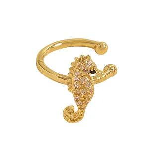 Macro view of a luxurious gold seahorse ear cuff encrusted with pink and clear zircons