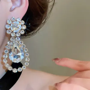 Nahaufnahme luxuriöser Tropfenohrringe mit Kristallen für Bräute am Ohr.