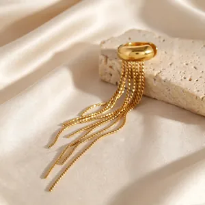 Macro detail of a gold stainless steel ear cuff with elegant long chain tassels on silk