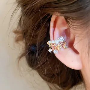 Detailed macro shot of an 18k gold plated ear cuff with sparkling zircon tassels on an ear
