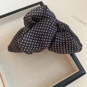Primer plano de pinza de pelo de nube con lunares negros y blancos y textura de malla plisada