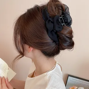 Primer plano de una pinza para el pelo negra de tela con volantes en un moño elegante.