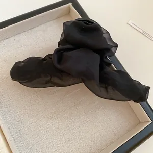 Detalle de una pinza para el pelo negra de tela plisada con un elegante estilo vintage